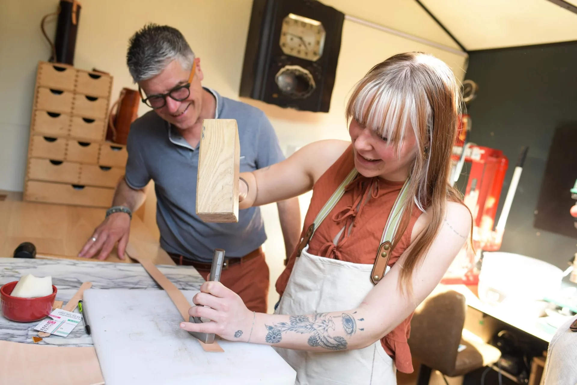 une jeune femme réalise sa ceinture avec des outils de maroquinerie